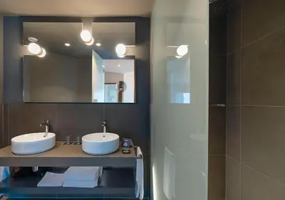 a bathroom with two sinks and a mirror and a shower at AQUA Hotel Promenade & Spa 4Sup in Pineda de Mar