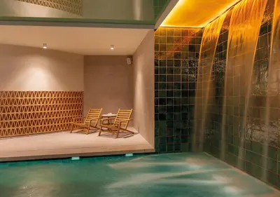 a swimming pool with two chairs and a table in a house at AQUA Hotel Promenade & Spa 4Sup in Pineda de Mar