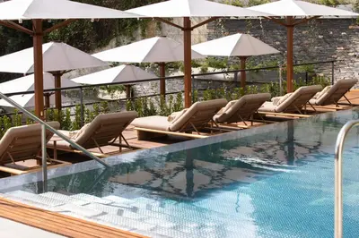 a row of chairs and umbrellas next to a swimming pool at METT Barcelona GL - A Leading Hotel of the World in Barcelona