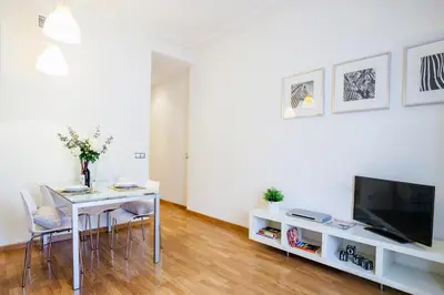 a white living room with a table and a tv at Feelathome Center Apartments in Barcelona