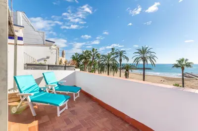 a balcony with two chairs and a view of the beach at Vistamar 2: Primera línea de mar con gran terraza in Sitges