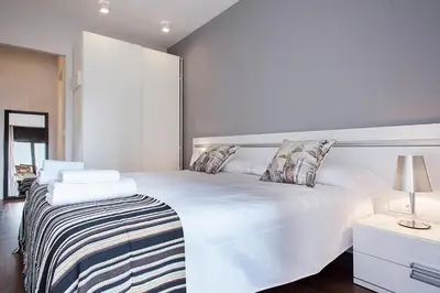 a white bedroom with a large white bed with pillows at Suites4days Provenza Apartment in Barcelona
