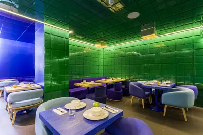 a restaurant with green walls and tables and purple chairs at Room Mate Carla, Barcelona in Barcelona
