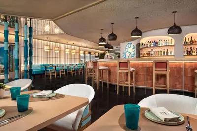a restaurant with tables and chairs and a bar at NH Collection Barcelona Constanza in Barcelona