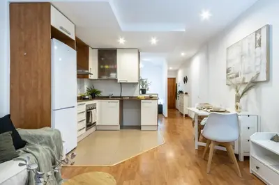 a kitchen with white cabinets and a table in a room at Fantástico loft cerca centro by Lofties in Terrassa