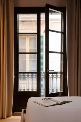 a bedroom with two windows and a bed with a book at Hotel Hamsa House in Barcelona