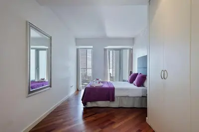 a bedroom with a bed with purple sheets and windows at Alcam Llum Deluxe in Barcelona