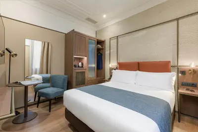 a hotel room with a bed and a desk and a chair at Hotel Medinaceli 4 Estrellas SUPERIOR in Barcelona