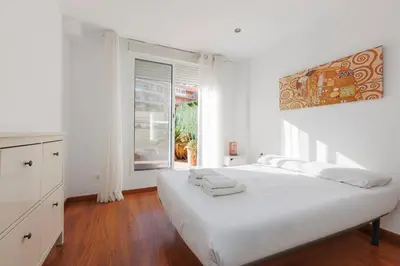 a white bedroom with a bed and a window at ApartEasy - Private Terrace, 3-Bedroom Apartment in Barcelona