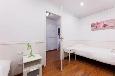 a white bedroom with a bed and a table at ApartEasy - Private Terrace, 3-Bedroom Apartment in Barcelona