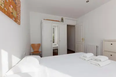 a white bedroom with a white bed with two towels at ApartEasy - Private Terrace, 3-Bedroom Apartment in Barcelona
