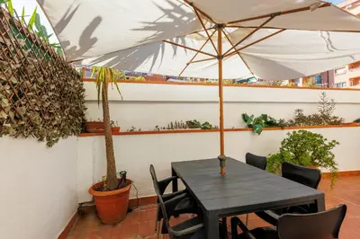 a black table and chairs with an umbrella at ApartEasy - Private Terrace, 3-Bedroom Apartment in Barcelona