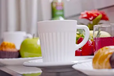 a white coffee cup sitting on a table with food at Barcelona City North Hostal in Barcelona