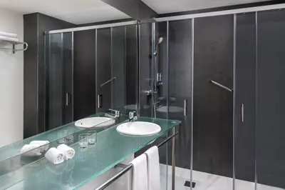 a bathroom with two sinks and a glass shower at Four Points by Sheraton Barcelona Diagonal in Barcelona