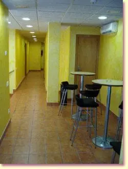 a hallway with tables and stools in a room at Llagotel in La Llagosta