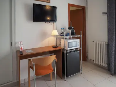a room with a desk with a microwave and a refrigerator at Hotel Montserrat in Sitges