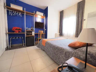 a bedroom with a bed and a blue wall at Hotel Montserrat in Sitges