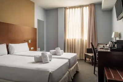 a hotel room with two beds and a desk at Hotel Madanis in Barcelona