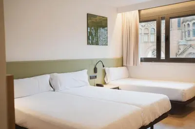 two beds in a hotel room with a window at Hotel Sant Pau in Barcelona