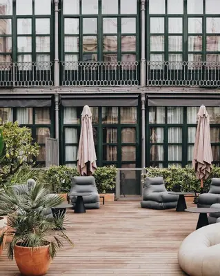 a building with chairs and umbrellas in a courtyard at ICON Bcn in Barcelona