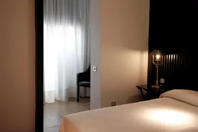 a bedroom with a bed and a window with a chair at Hotel Market in Barcelona