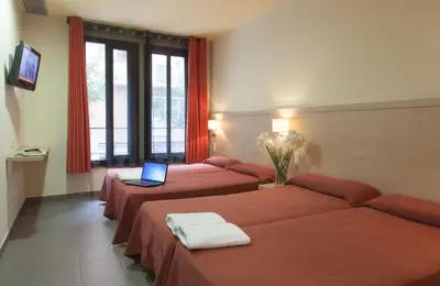 a room with three beds with a laptop on them at Residència Erasmus Gracia in Barcelona