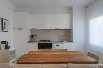 a kitchen with white cabinets and a wooden table at Mare Nostrum: En el corazón de Sitges in Sitges