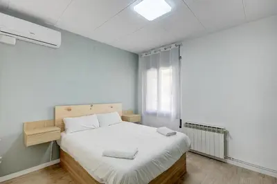 a bedroom with a bed with white sheets and a window at Barcelona Beach Vibes in Sant Adria de Besos