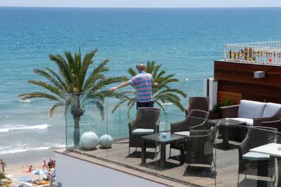 a man standing on a balcony looking at the ocean at Platjador in Sitges