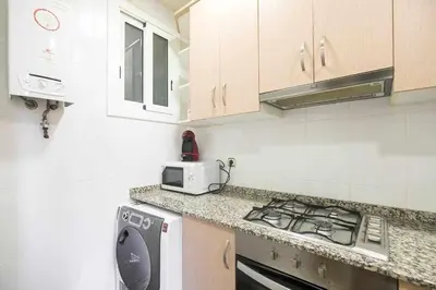a white kitchen with a stove and a microwave at Consell Cent apartment I 3 dormitorios Eixample in Barcelona
