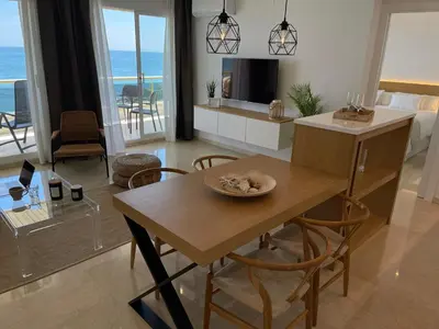 a living room with a dining table and a room with the ocean at Mediterraneo Sitges in Sitges