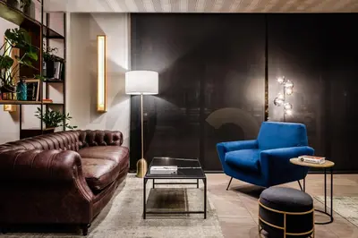a living room with a leather couch and a blue chair at Hotel HC*** Mollet Barcelona in Mollet del Vallès