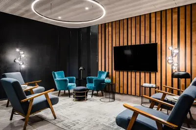 a waiting room with blue chairs and a flat screen tv at Hotel HC*** Mollet Barcelona in Mollet del Vallès