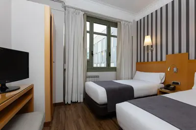 a hotel room with two beds and a television at Hotel Lyon in Barcelona