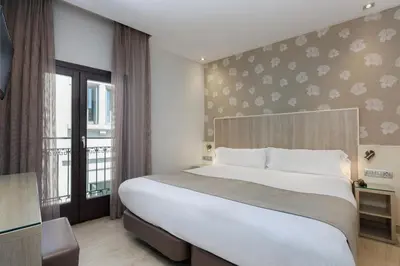 a bedroom with a large bed and a balcony at Hotel Santa Marta in Barcelona