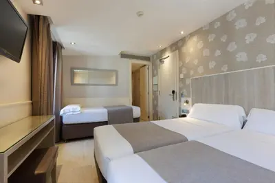 a hotel room with two beds and a flat screen tv at Hotel Santa Marta in Barcelona