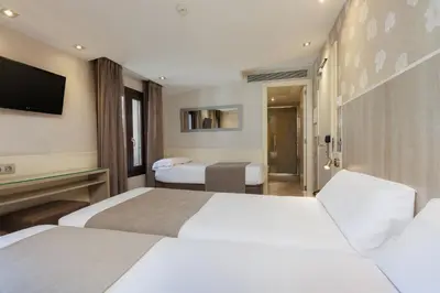 a hotel room with two beds and a television at Hotel Santa Marta in Barcelona