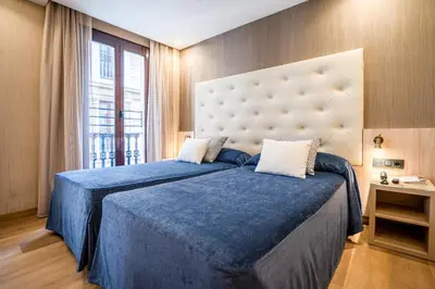 a bedroom with a blue bed with a large window at Hotel Rialto in Barcelona
