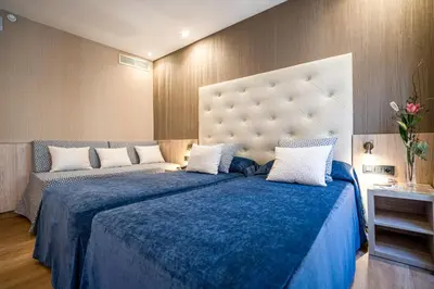 a bedroom with a large bed with a blue blanket at Hotel Rialto in Barcelona