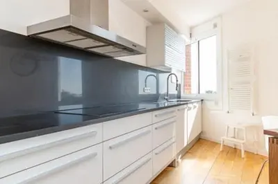 a kitchen with white cabinets and a black counter top at Idyllic apartment in BCN beach in Barcelona