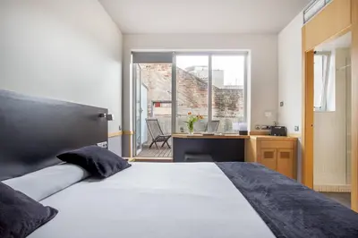 a bedroom with a bed and a desk and a window at Onix Liceo in Barcelona