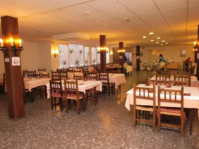 a dining room with tables and chairs and a person at El Cid in Sitges
