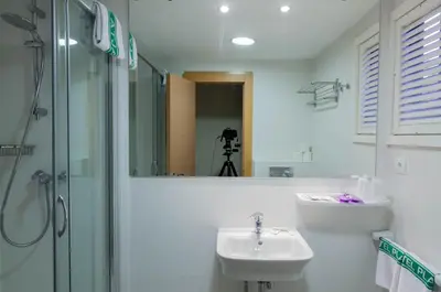 a bathroom with a sink and a shower and a mirror at El Cid in Sitges