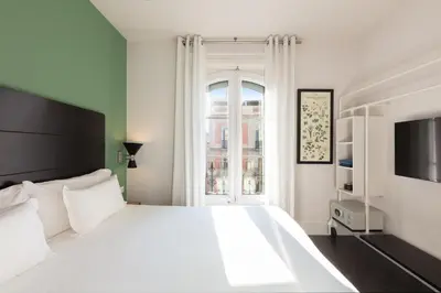 a white bedroom with a large bed and a window at Praktik Garden in Barcelona
