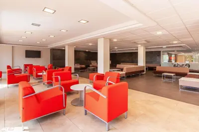 a waiting room with red chairs and tables at Checkin Montserrat in Collbató