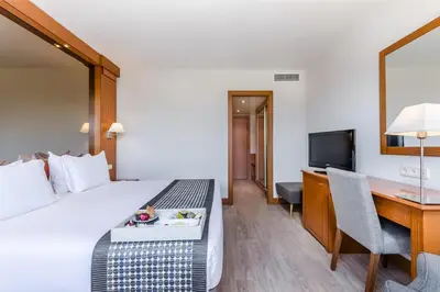 a hotel room with a bed and a desk and a television at Exe Campus in Bellaterra