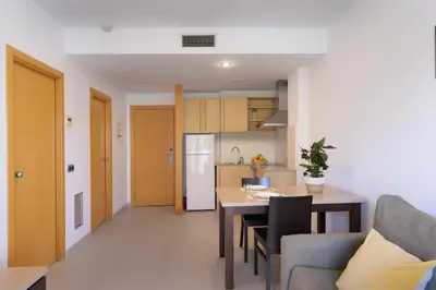 a living room and kitchen with a table and a couch at SG Costa BCN Apartments in Castelldefels