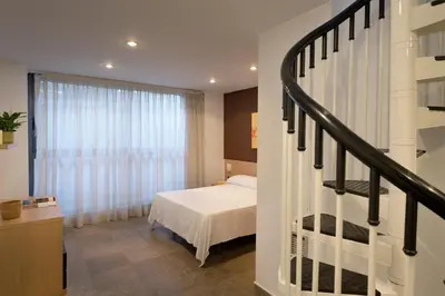 a bedroom with a bed and a staircase in front of a window at SG Costa BCN Apartments in Castelldefels