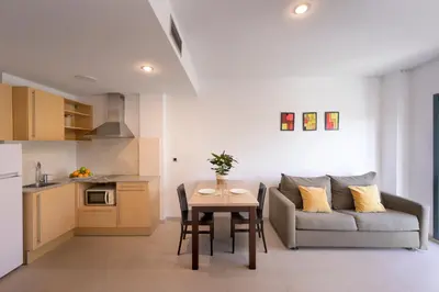 a kitchen and a living room with a table and a couch at SG Costa BCN Apartments in Castelldefels