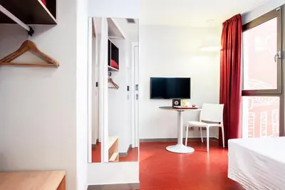 a bedroom with a bed and a desk with a television at Ciutat Vella in Barcelona